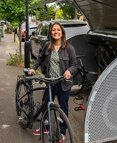 Woman smiling with bike in front of hooplr bikehangar